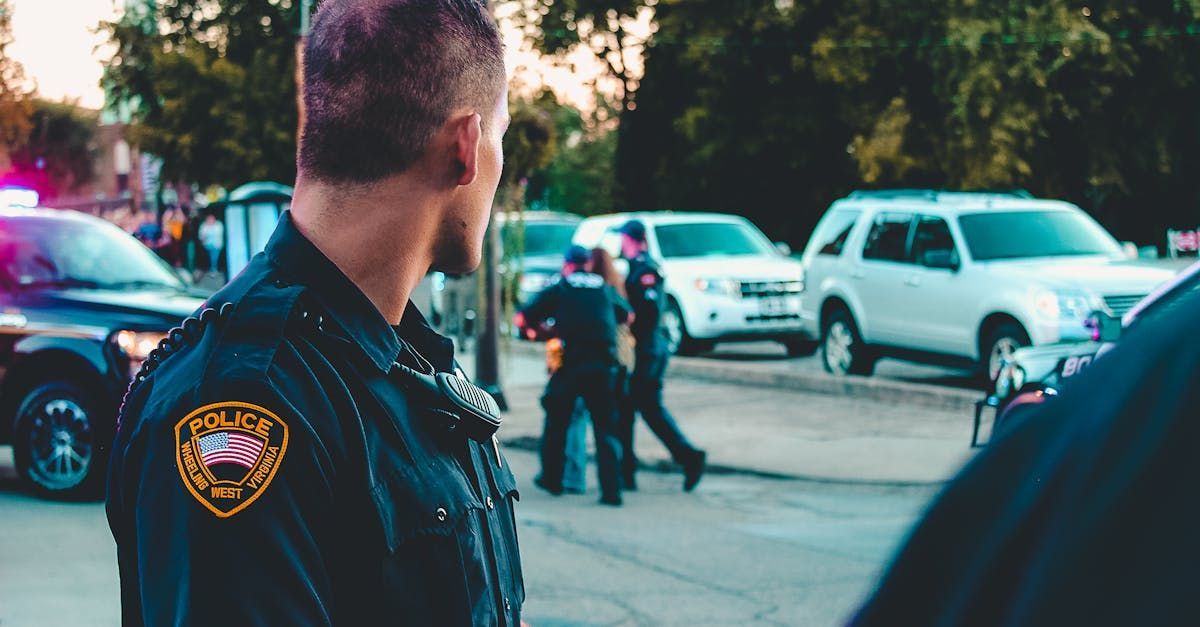 Officer watching other officers take a person away.