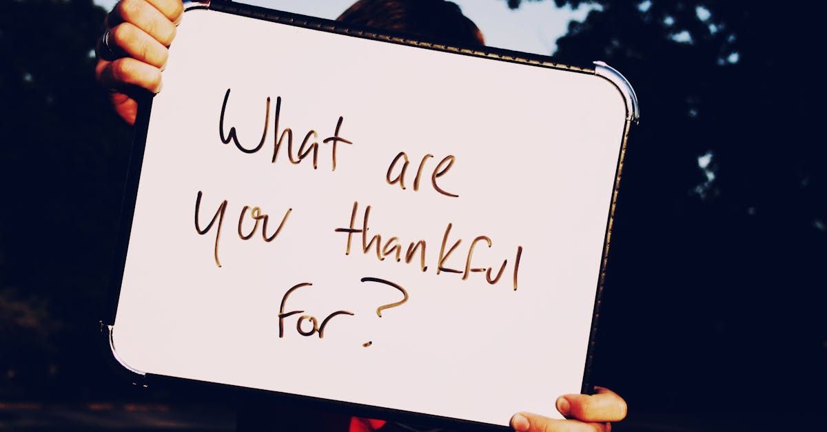 A person is holding a sign that says what are you thankful for ?