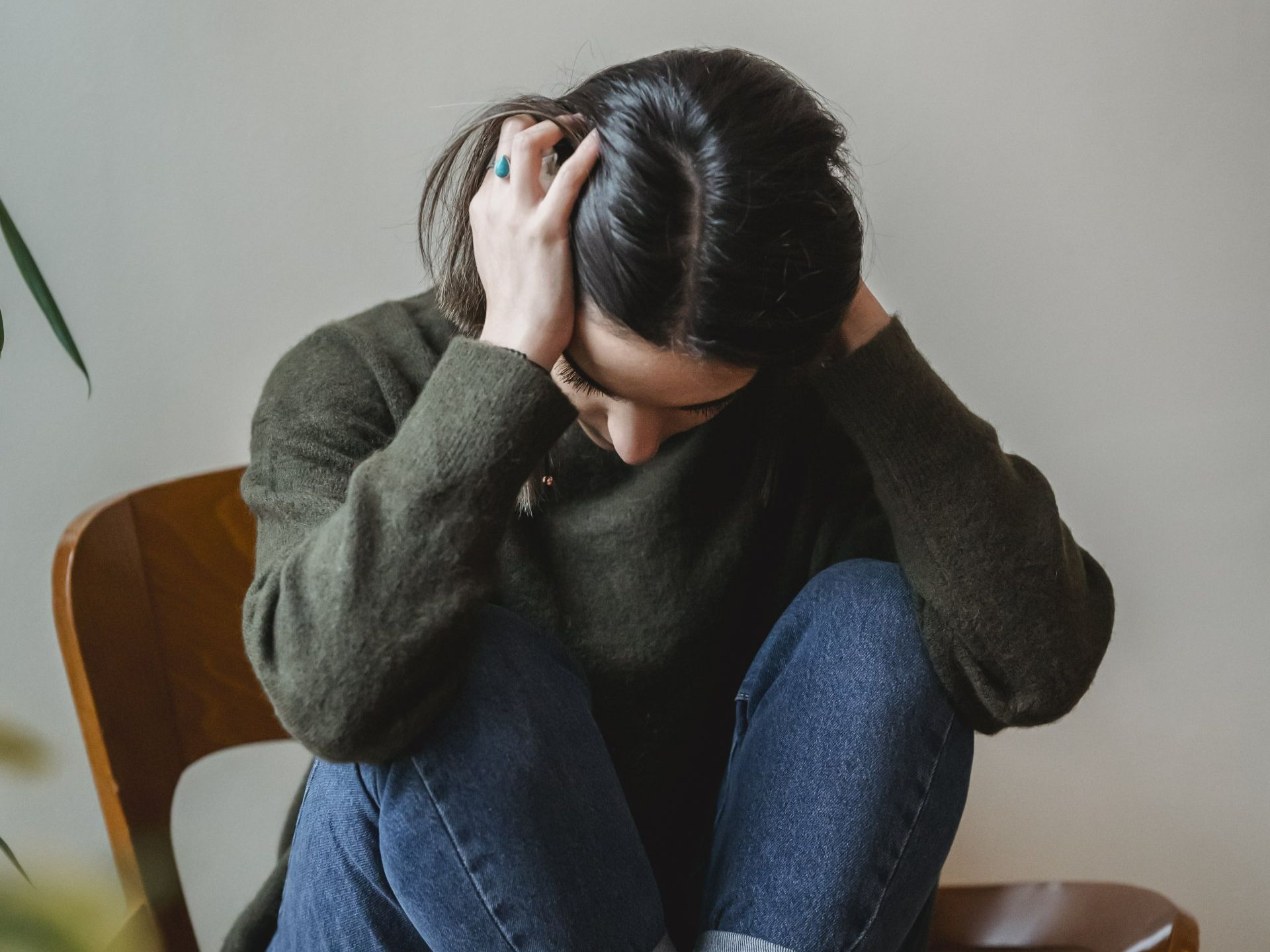 A woman is sitting in a chair with her head in her hands.