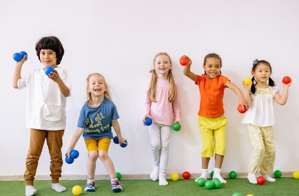 A group of children are standing next to each other holding dumbbells.