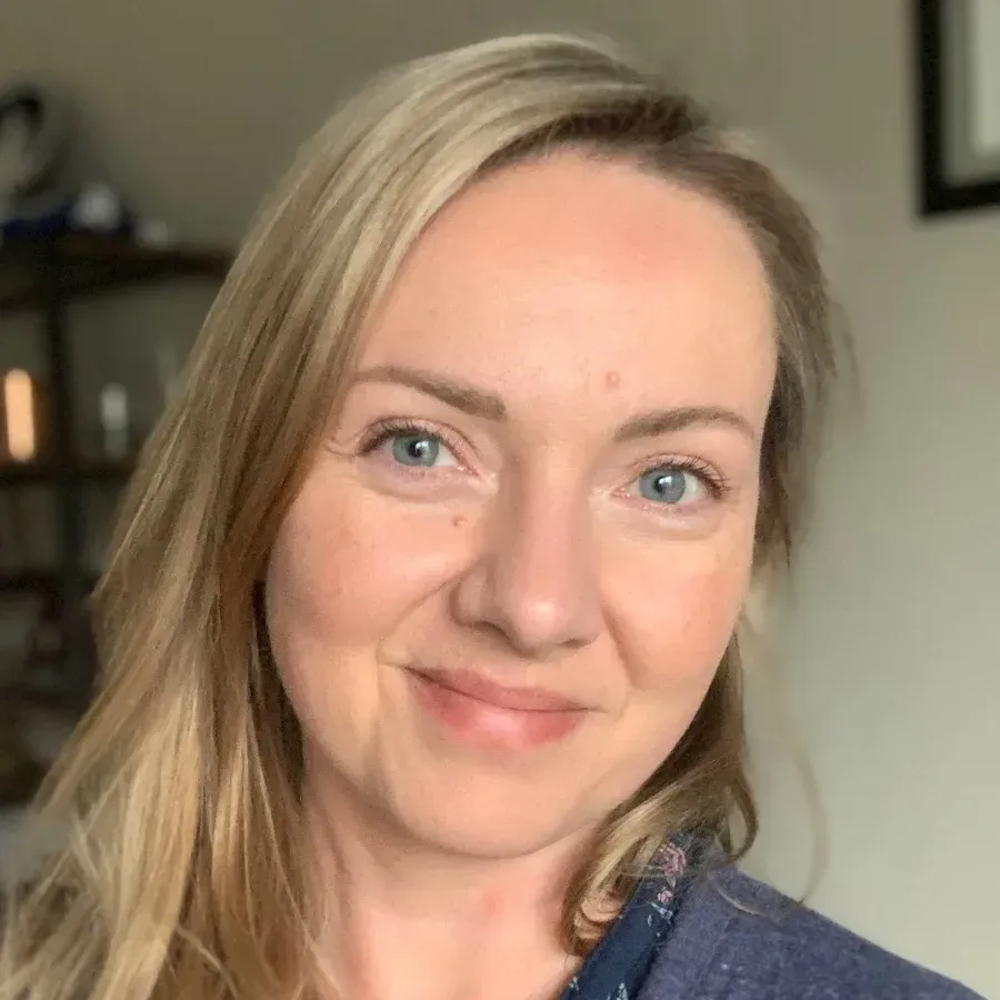 A woman with blonde hair and blue eyes is smiling for the camera.