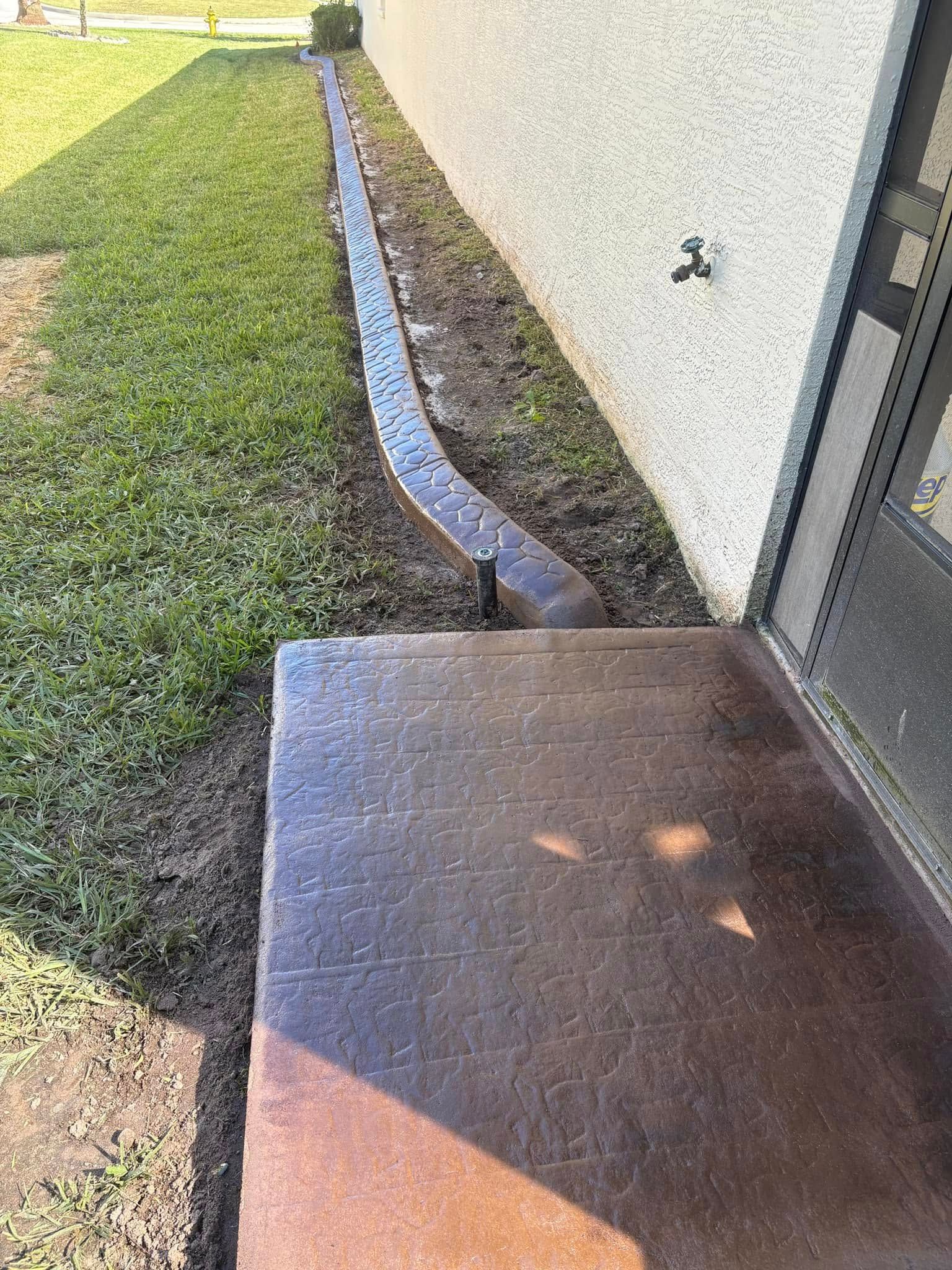 A concrete curb is being installed on the side of a building.