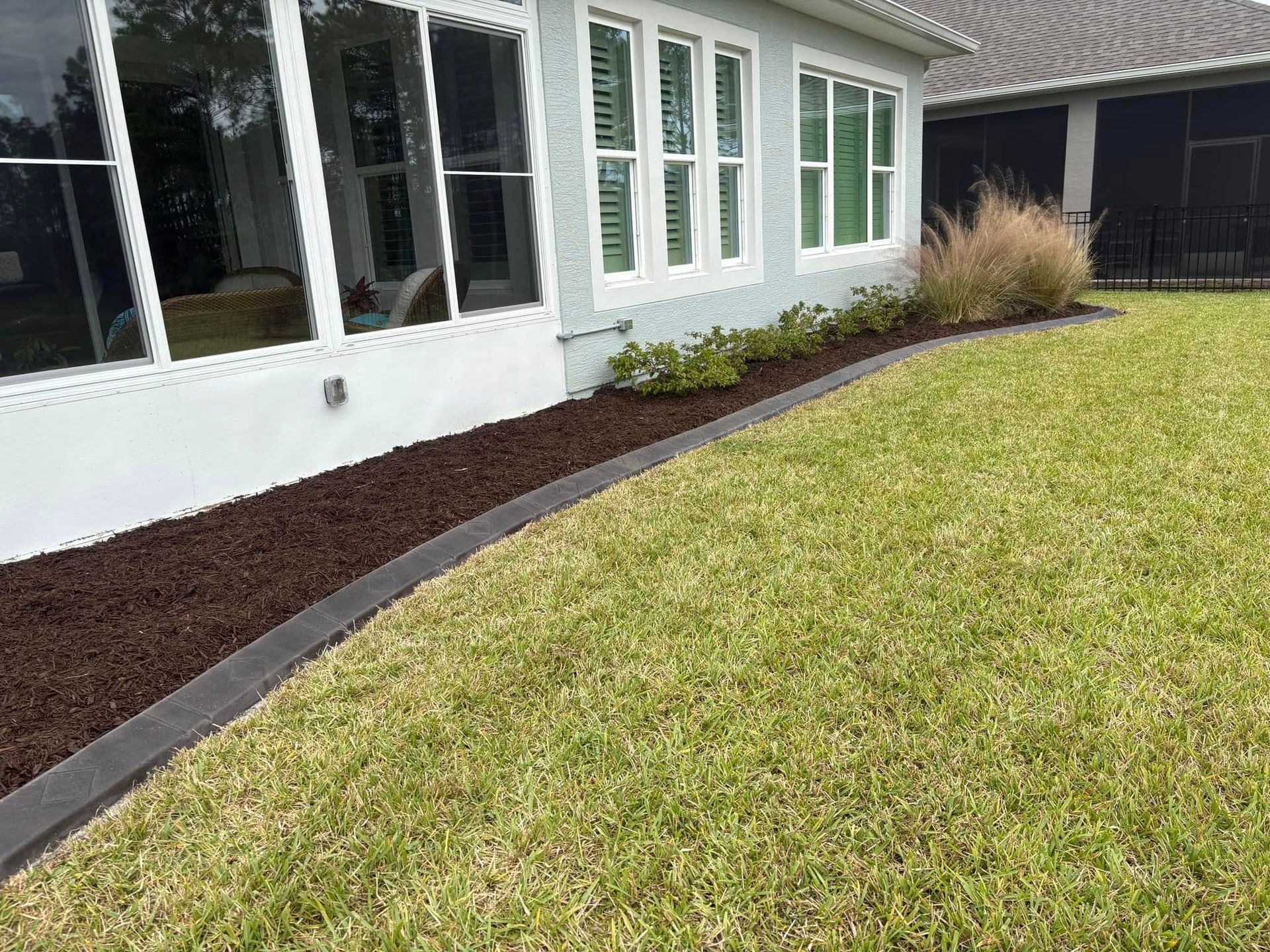 A house with a lot of windows and a lush green lawn in front of it.