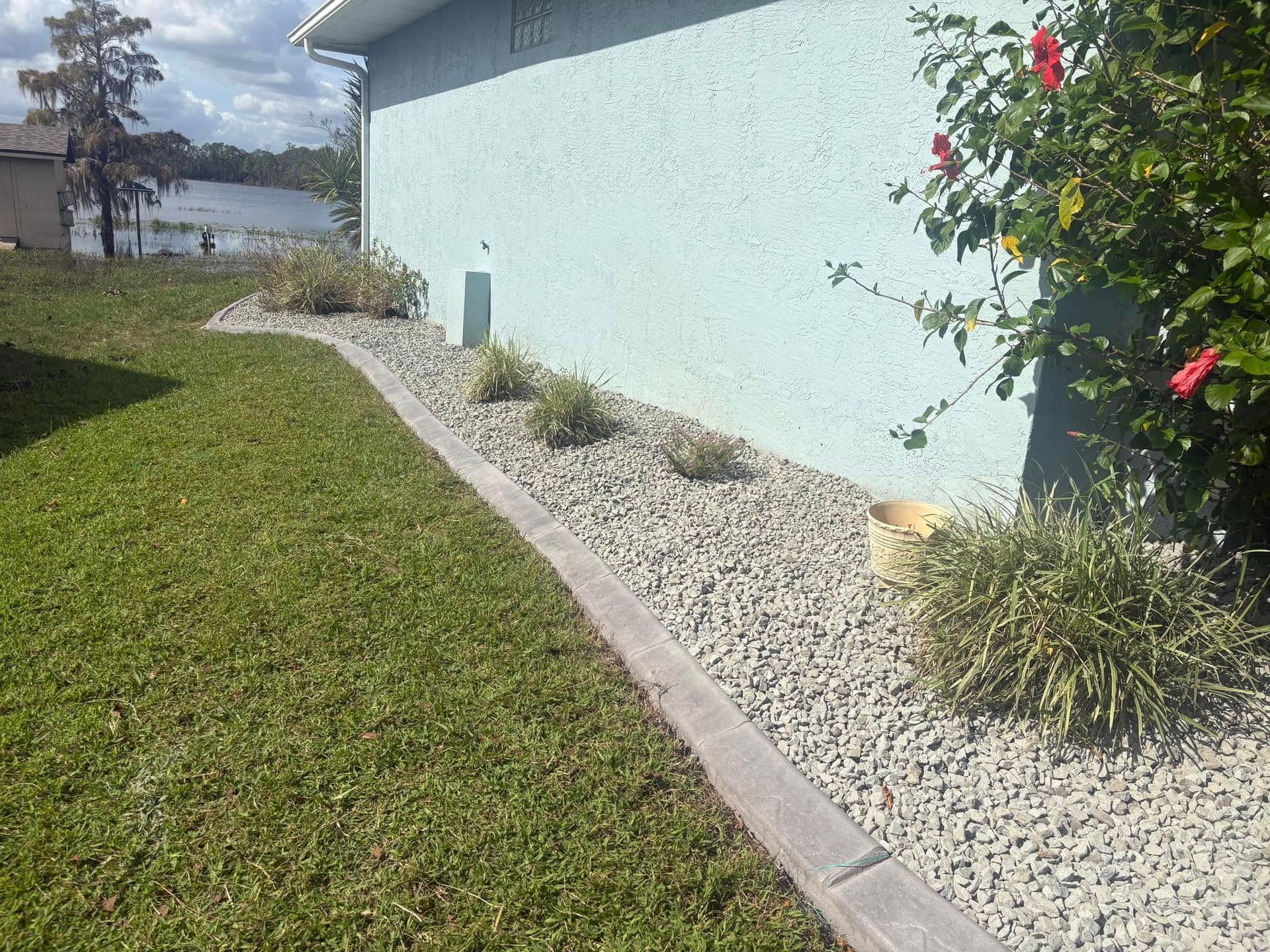 A house with a lush green lawn and gravel in front of it.