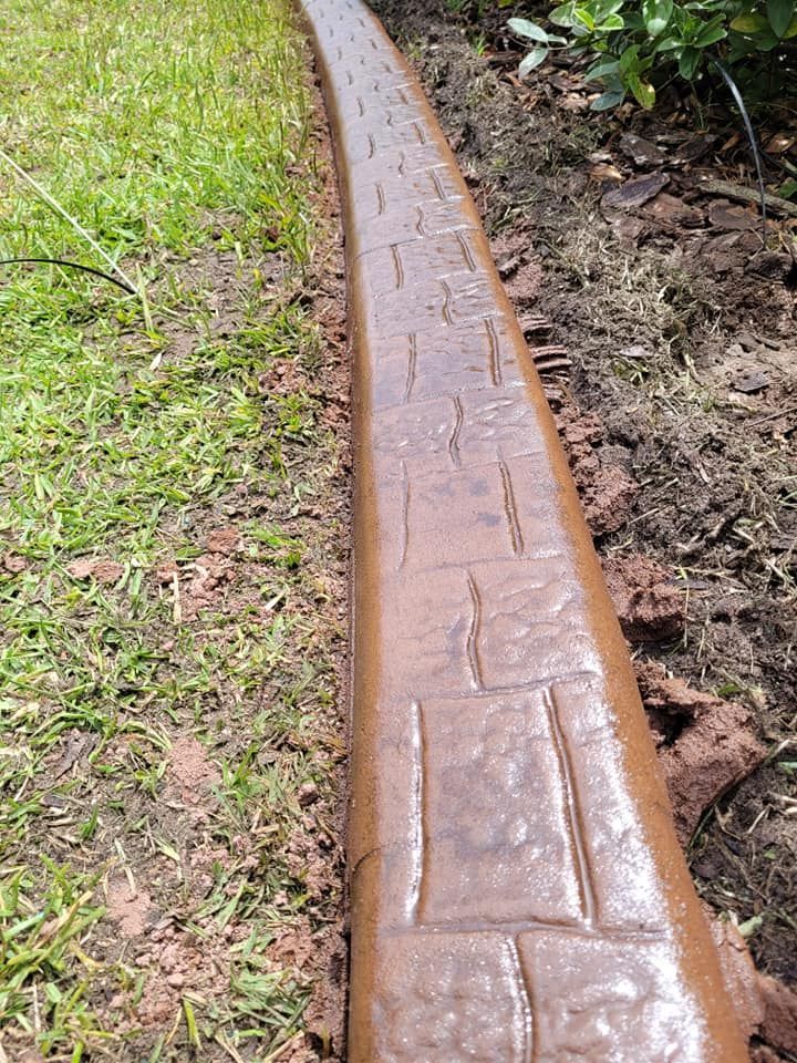 A brown concrete curb is sitting on top of a lush green lawn.