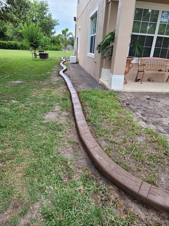 A concrete curb is being installed in front of a house.