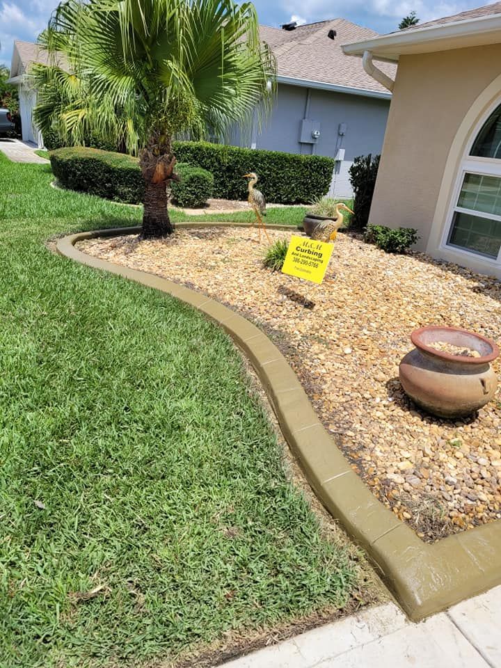 A lawn with a concrete curb and a potted plant in front of a house.