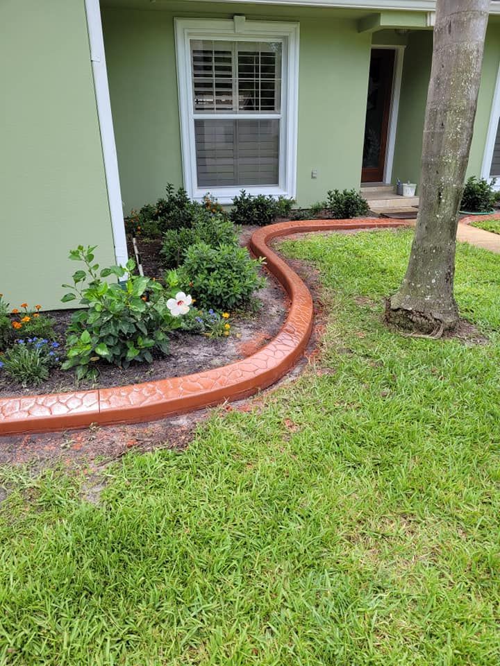 A lawn with a curb and a tree in front of a house.