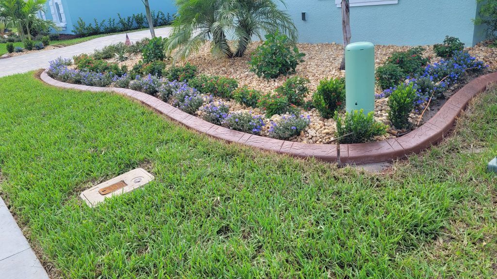 A lush green lawn with flowers and shrubs in front of a house.
