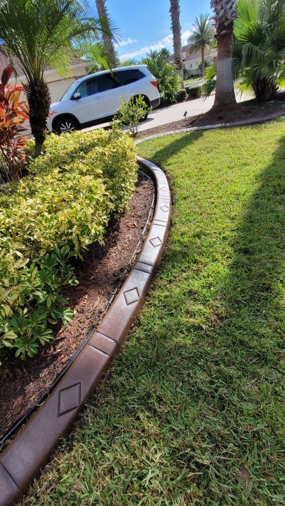 A white van is parked on the side of the road next to a lush green lawn.