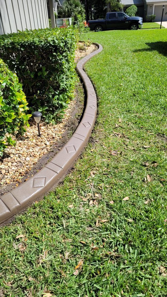 A concrete curb is sitting in the middle of a lush green lawn.