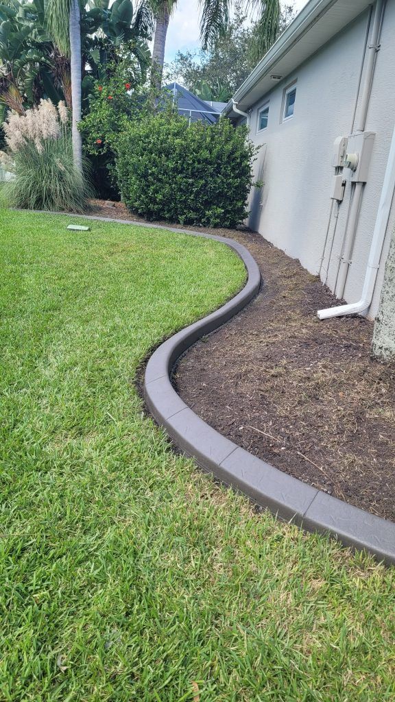 A lawn with a concrete curb and a house in the background.