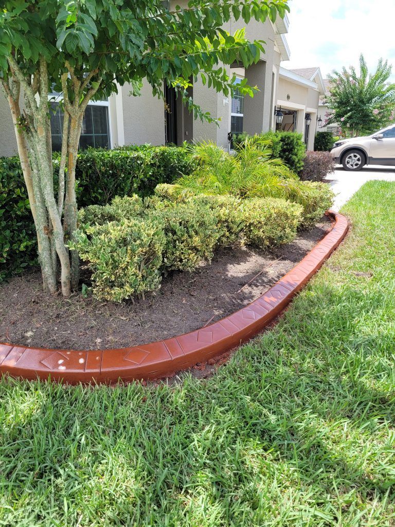 A car is parked in front of a house with a concrete curb.