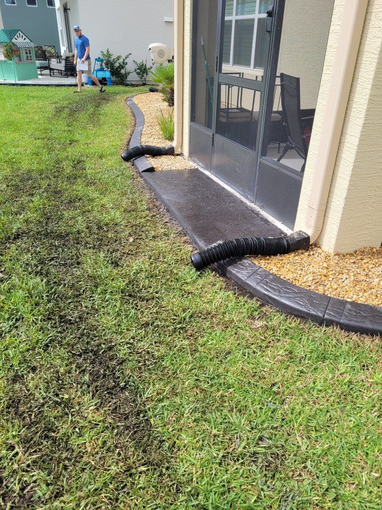 A man is mowing the grass in front of a screened in porch.