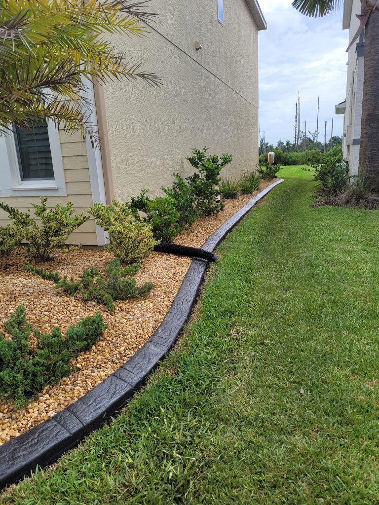A lawn with a concrete curb and a house in the background.