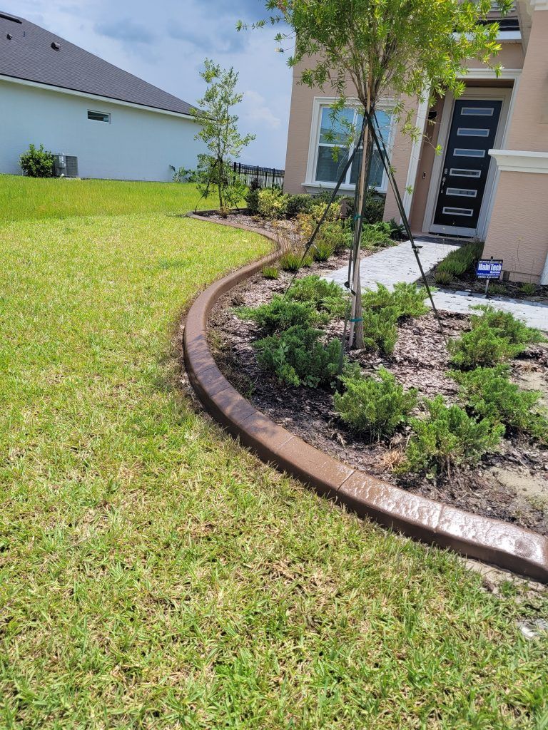 A concrete curb is surrounded by a lush green lawn in front of a house.
