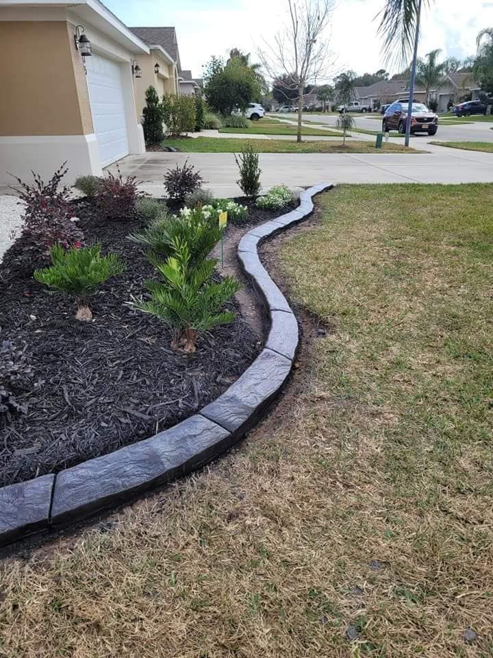 A curved concrete curb surrounds a garden in front of a house.