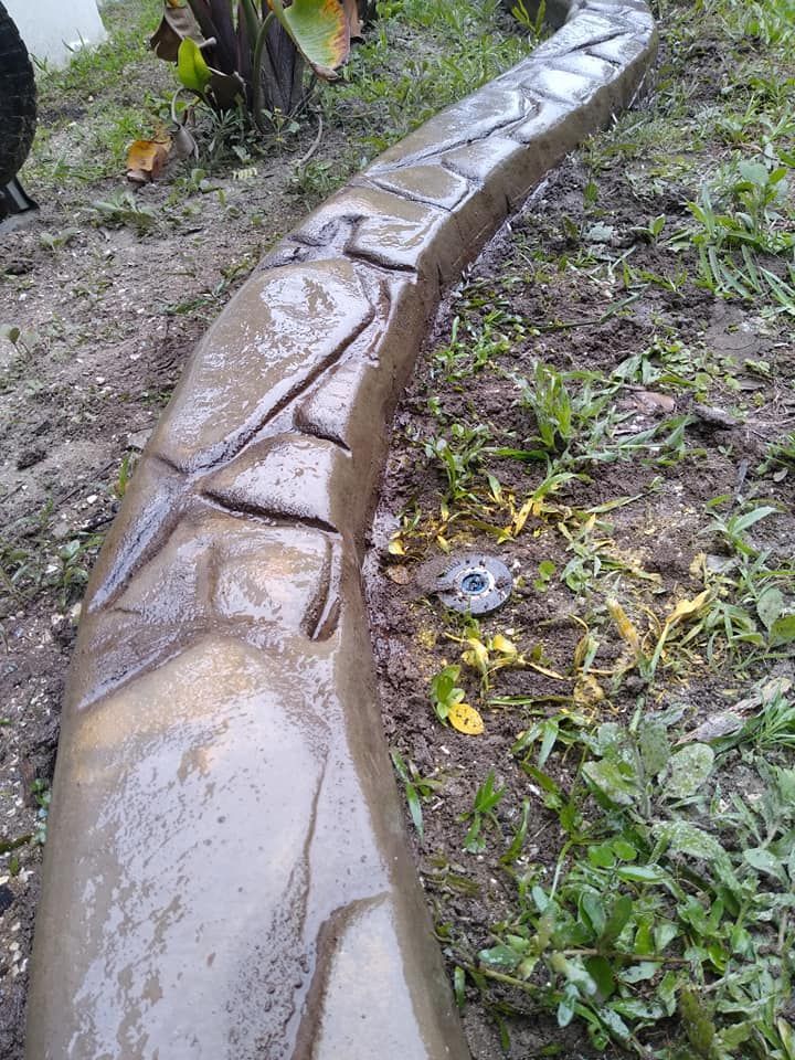 A concrete curb is sitting in the middle of a grassy field.
