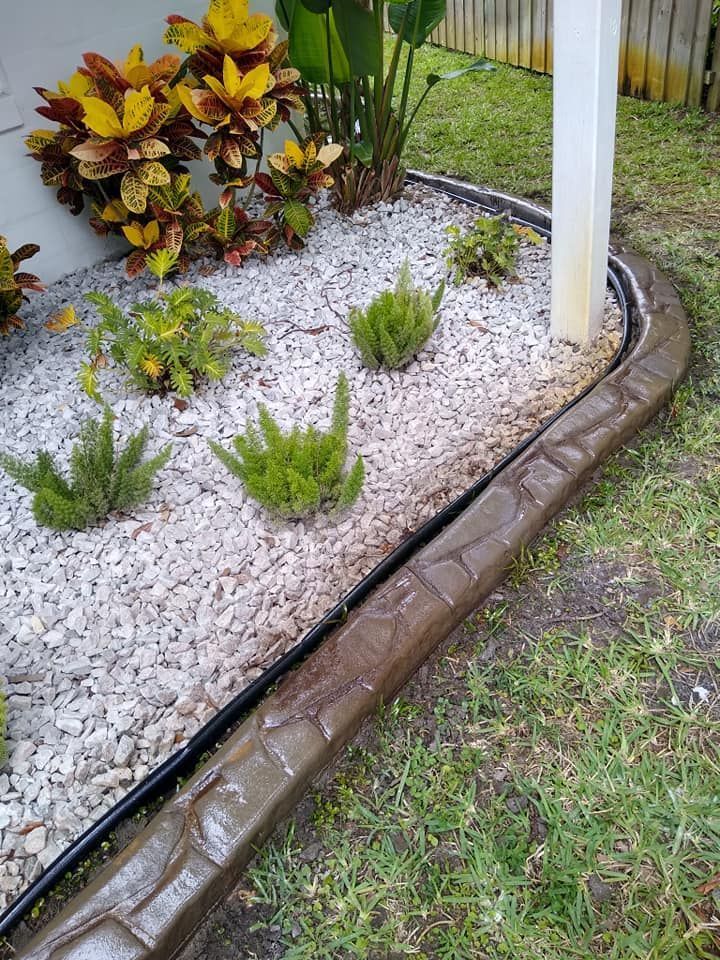 A garden filled with rocks and plants next to a house.