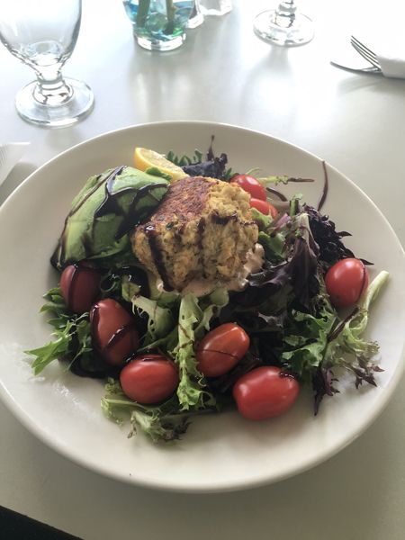 A white plate topped with a salad and a crab cake