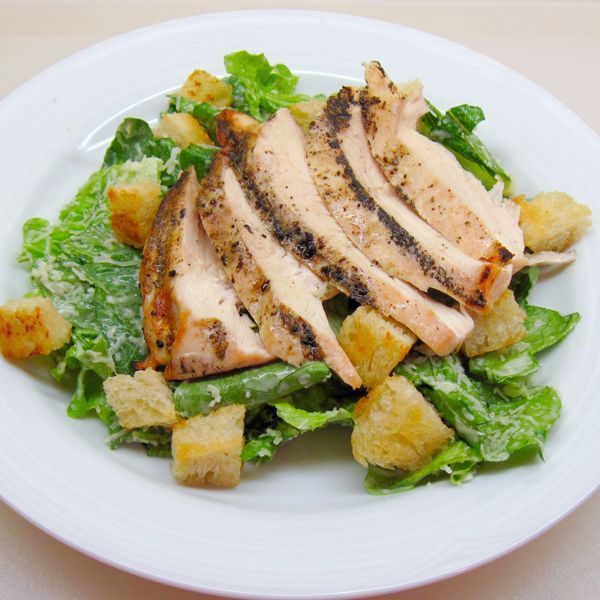 A white plate topped with chicken lettuce and croutons