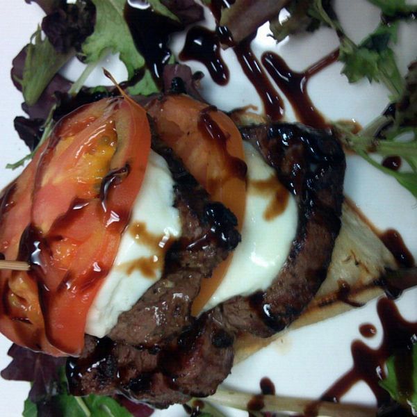 A close up of a plate of food with meat and tomatoes