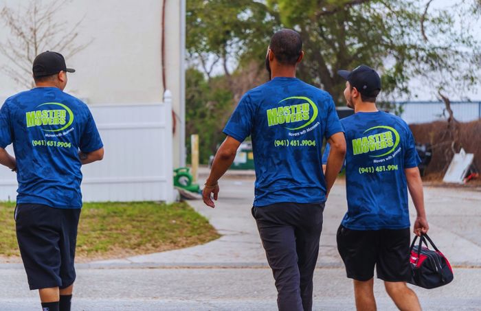 Three men in blue shirts are walking down a street.