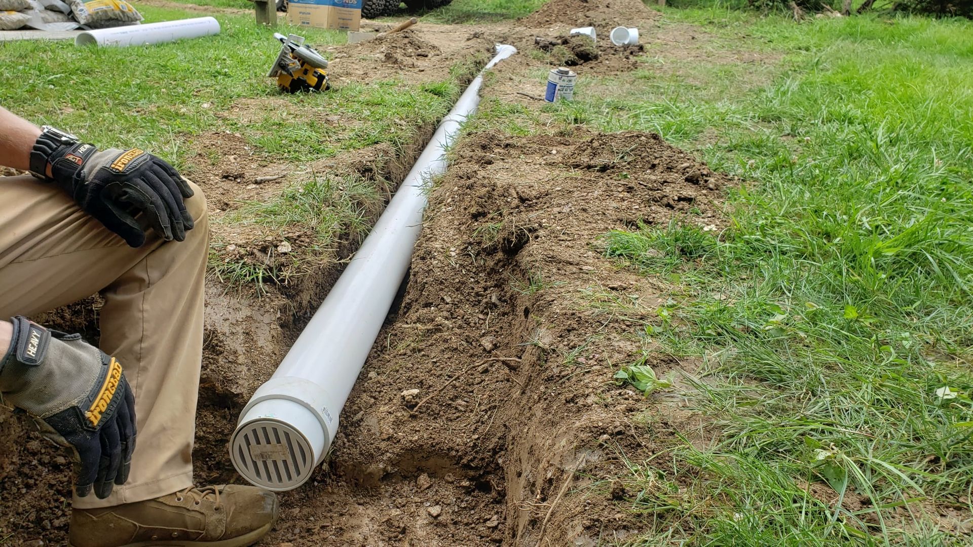 A person is laying a pipe in the dirt.