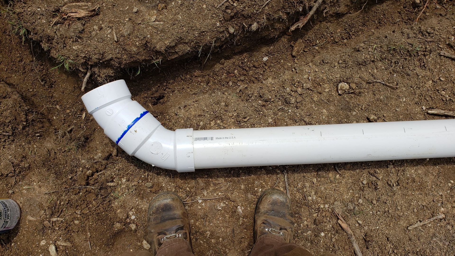 A person is standing next to a white pipe on the ground.