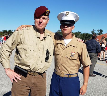 A man wearing headphones and sunglasses stands next to another man