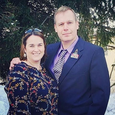 A man and a woman posing for a picture in front of a tree