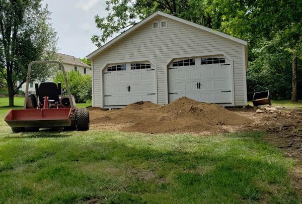A red tractor is parked in front of a garage.