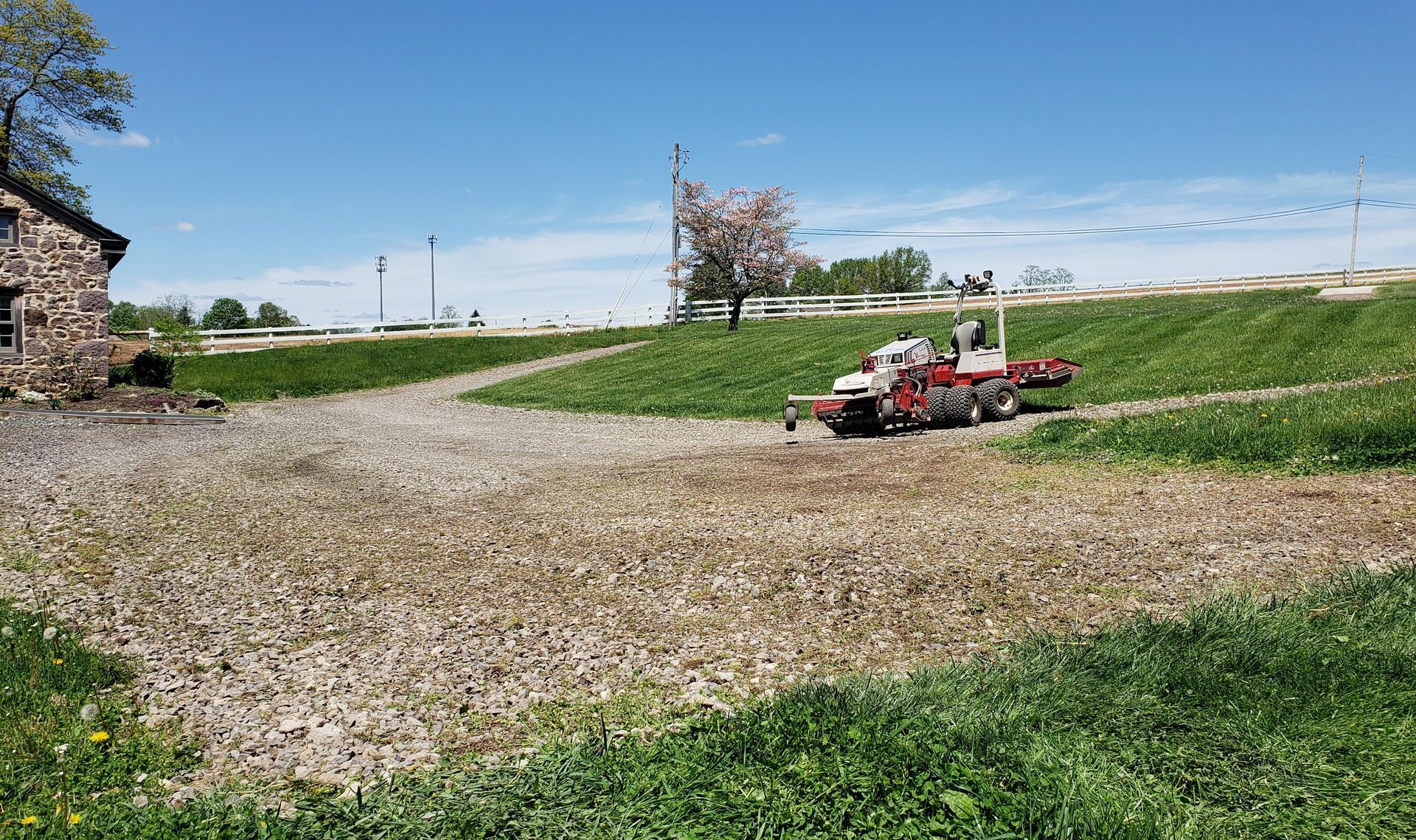 A tractor is driving down a dirt road in a field.