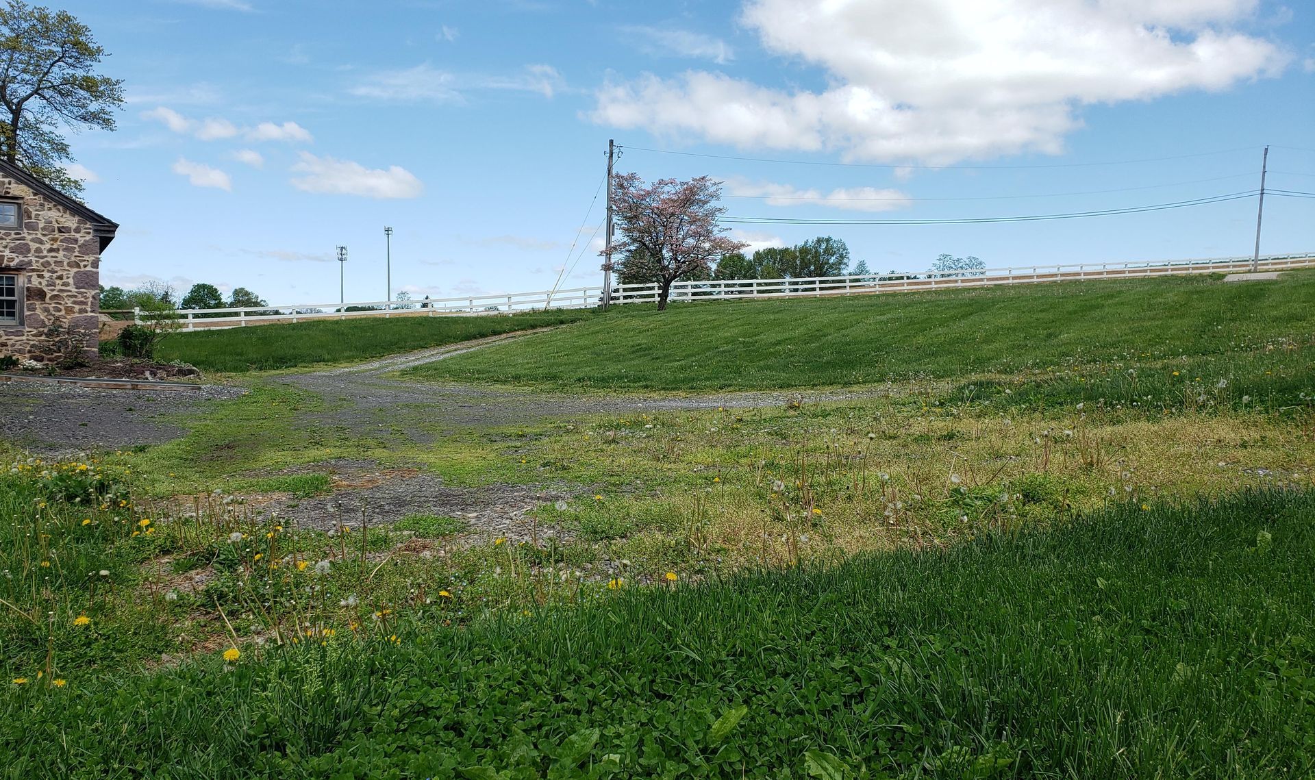 A large grassy field with a stone building in the background.