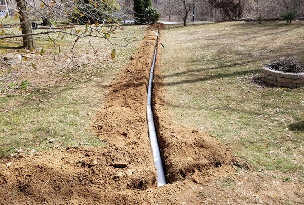 A pipe is being installed in the dirt in a yard.