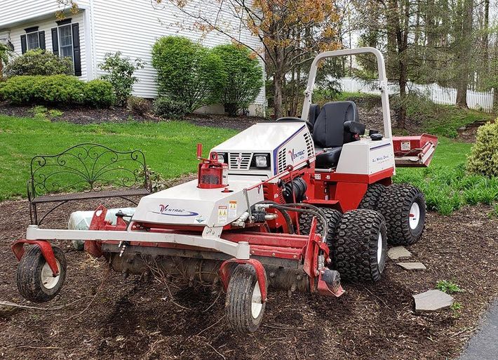 A red and white lawn mower is parked in front of a house.