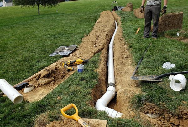 A man is digging a hole in the ground to install a pipe.