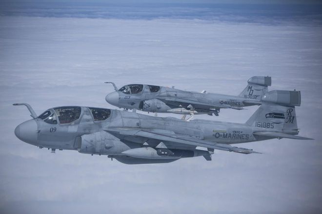 Two fighter jets are flying in the sky above the clouds.