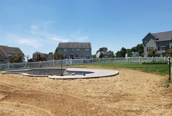 A swimming pool is being built in the middle of a dirt field.