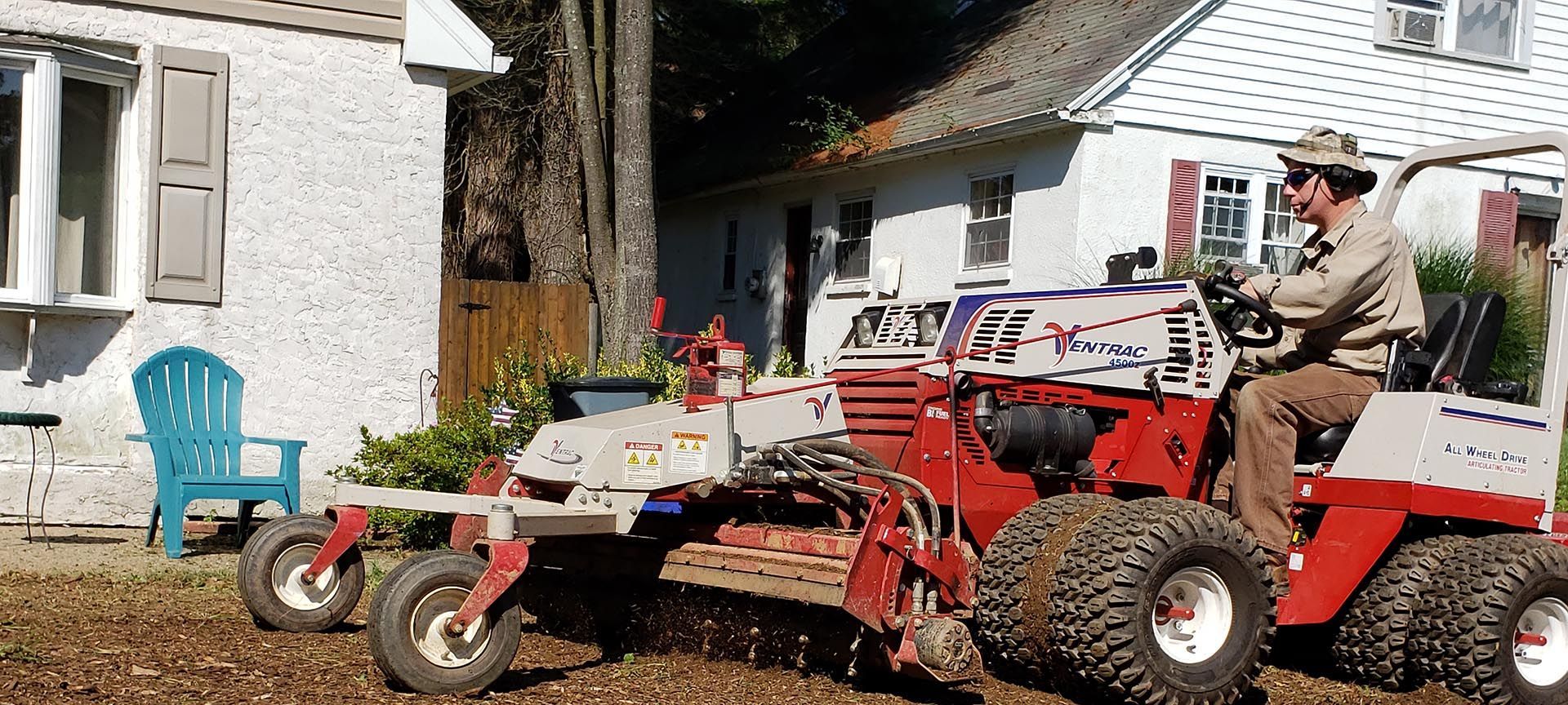 A man is driving a lawn mower in front of a house.