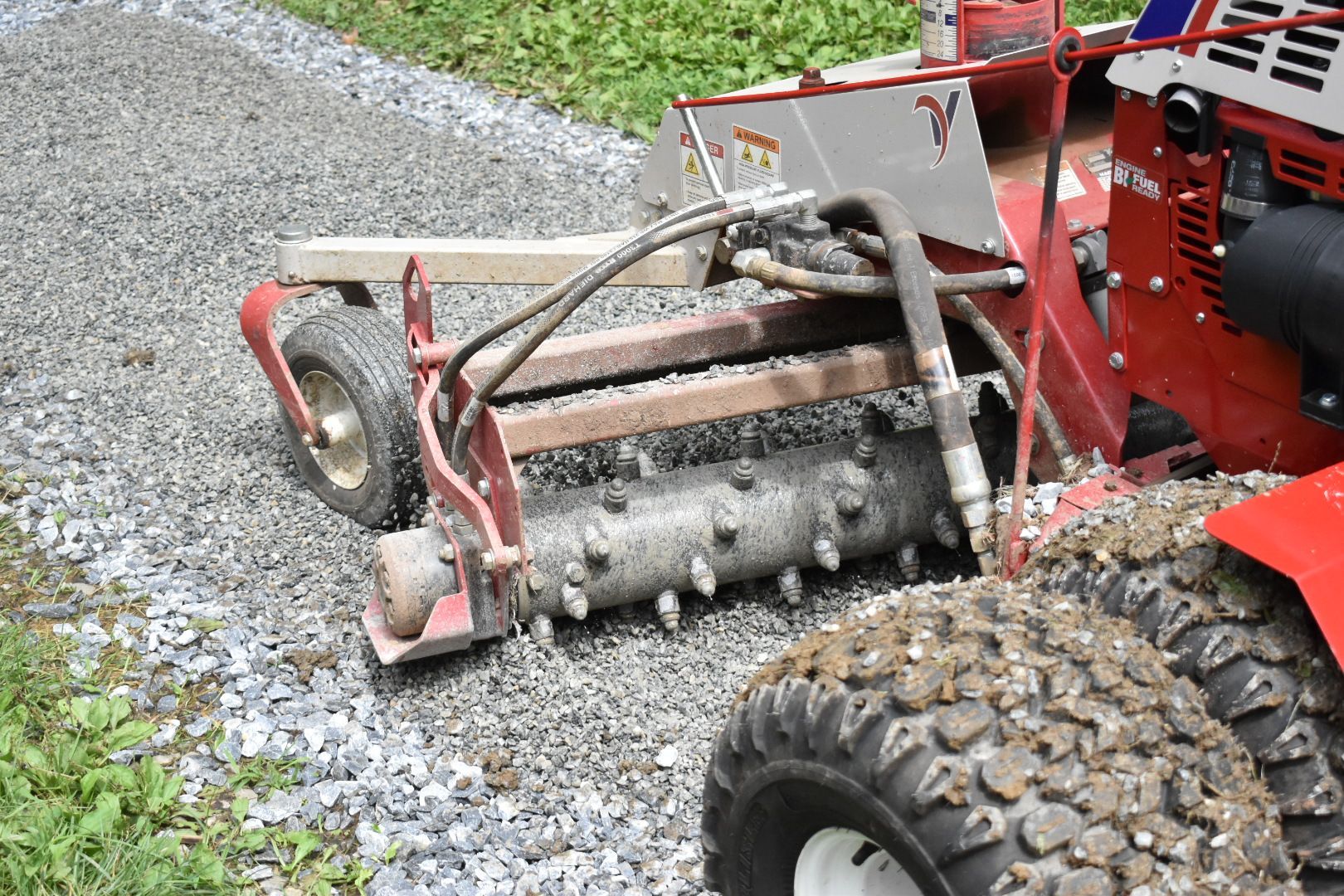 A red tractor is driving down a gravel road.