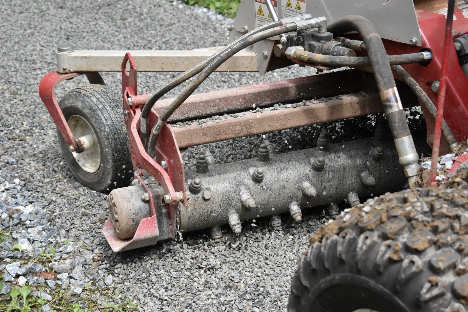 A machine is sitting on a gravel road next to a tire.