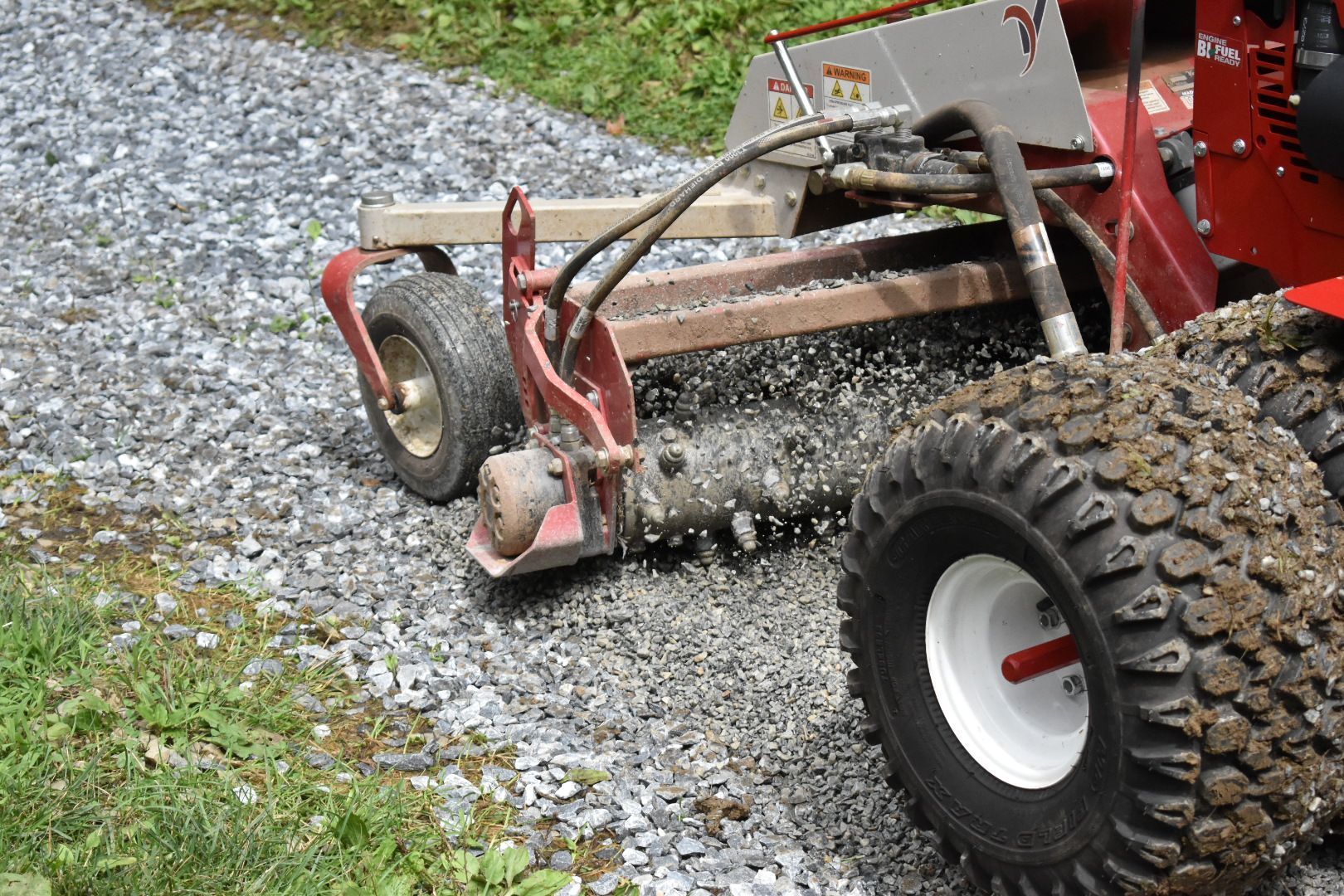 A red tractor is driving down a gravel road.