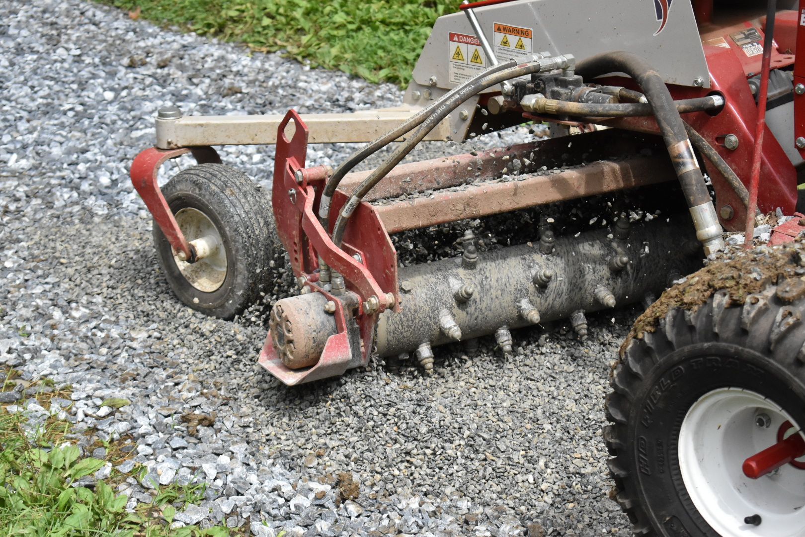 A red and white tractor is driving down a gravel road.