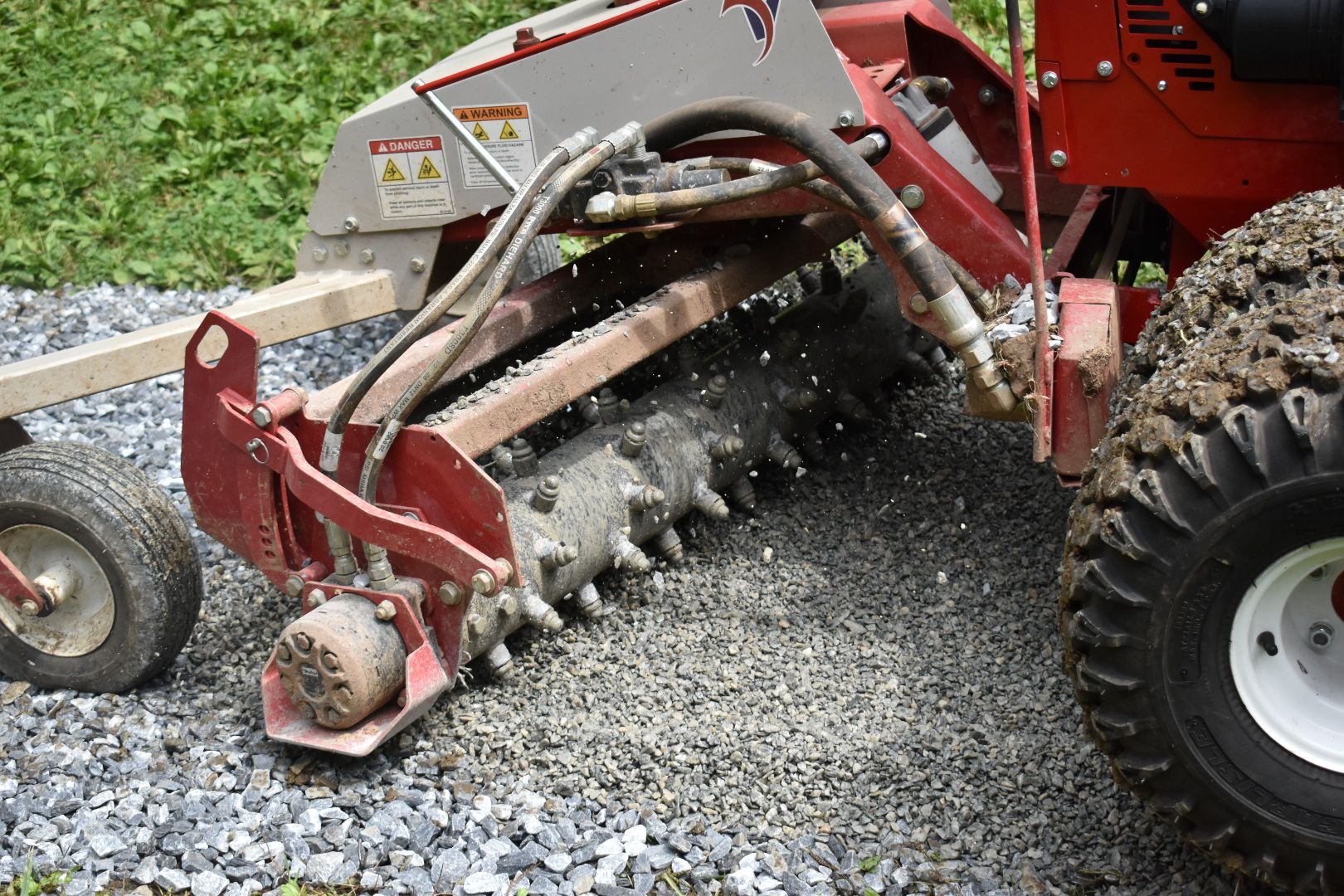 A red and white tractor is sitting on a gravel road.