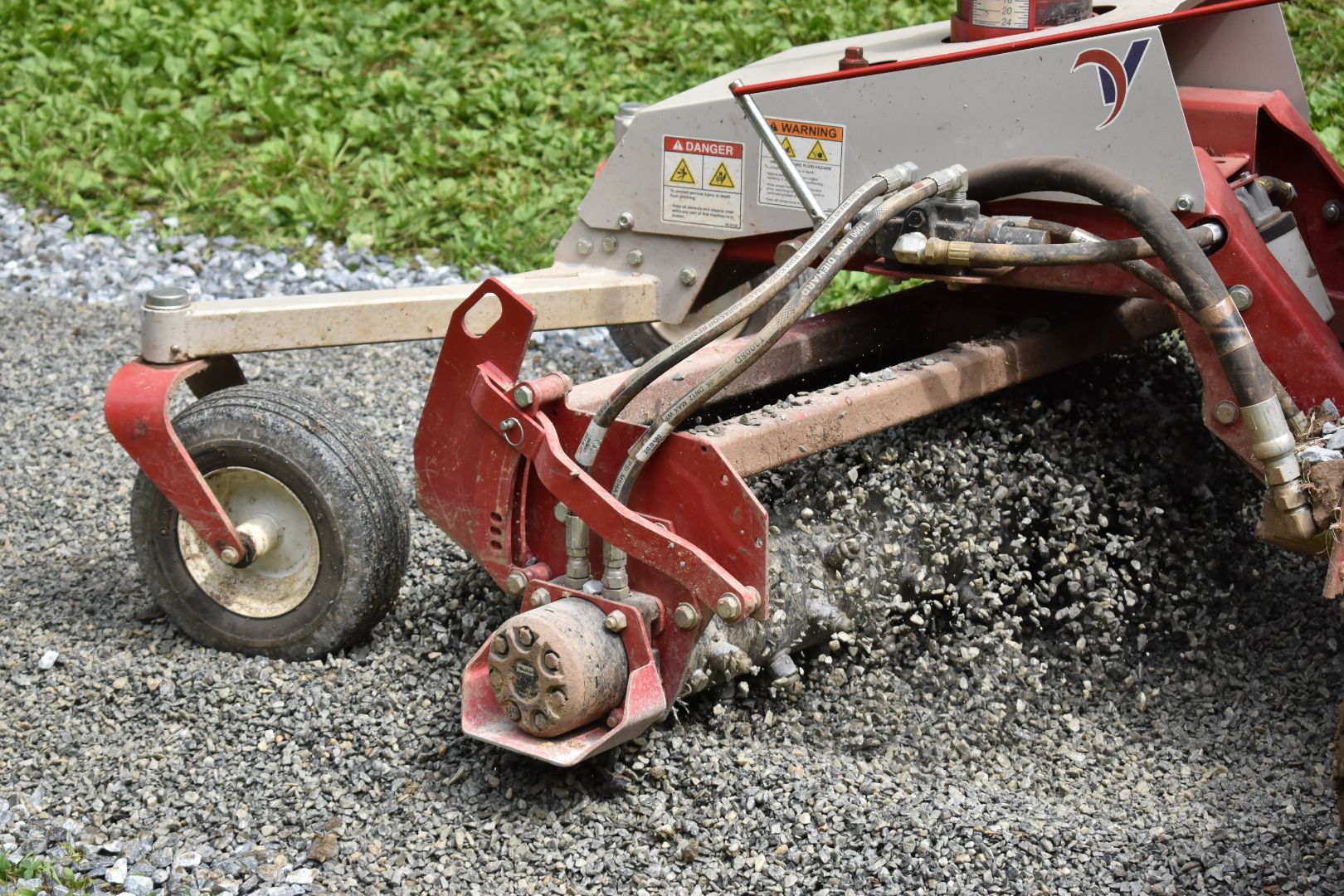 A red and white machine is sitting on a gravel road.