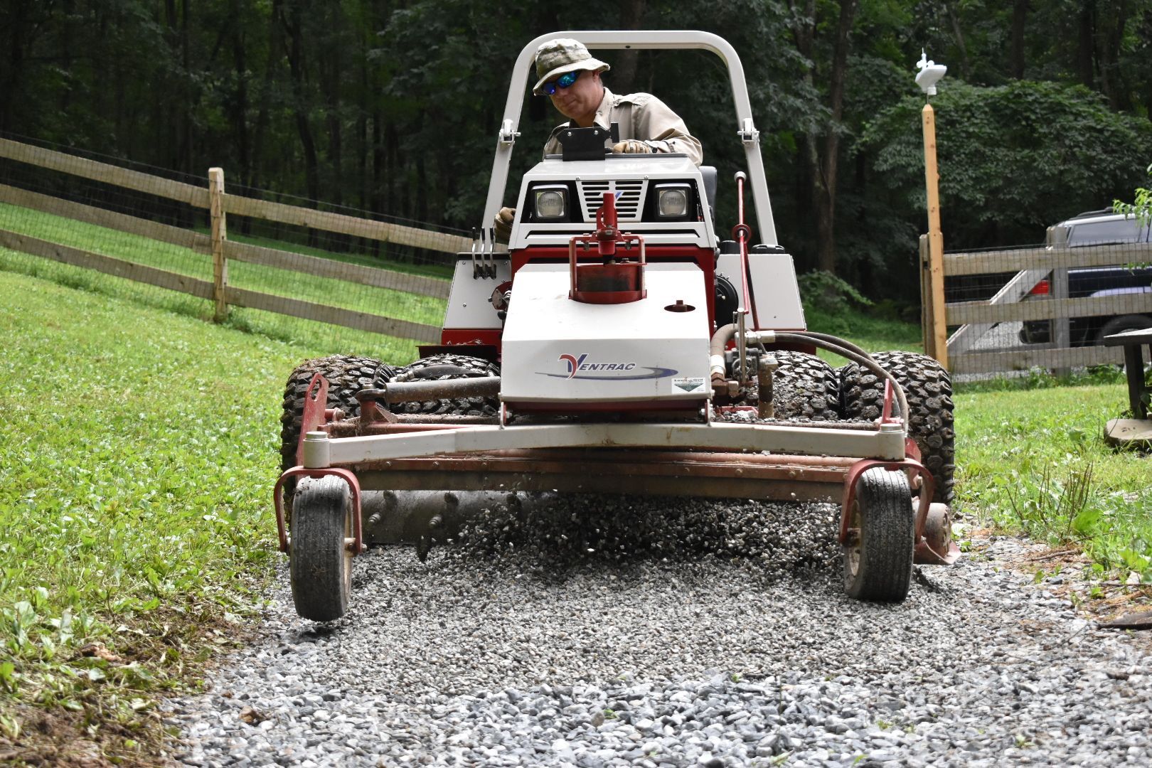 A man is driving a lawn mower on a gravel road