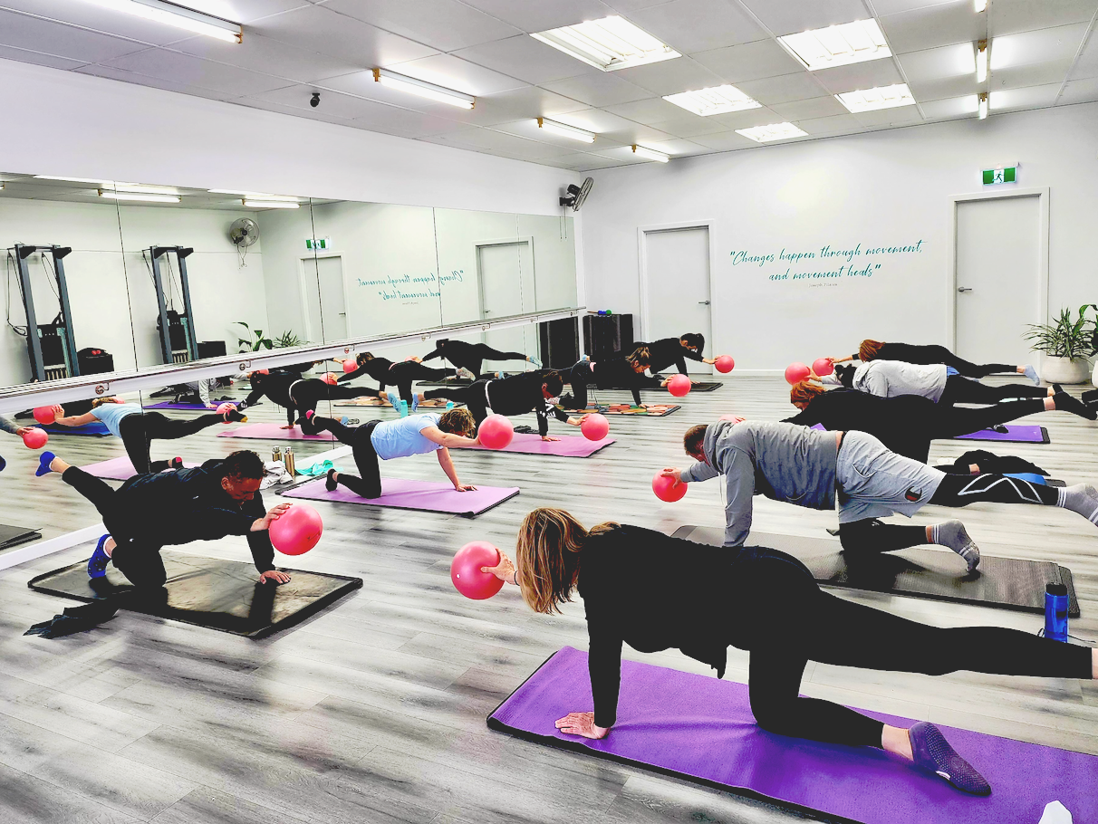 men and Women exercing in a Matwork class at Good Vibes Pilates Studio