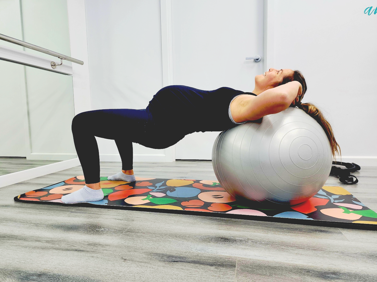 Pregnant woman exercising on a yoga mat with a Pilates Ball