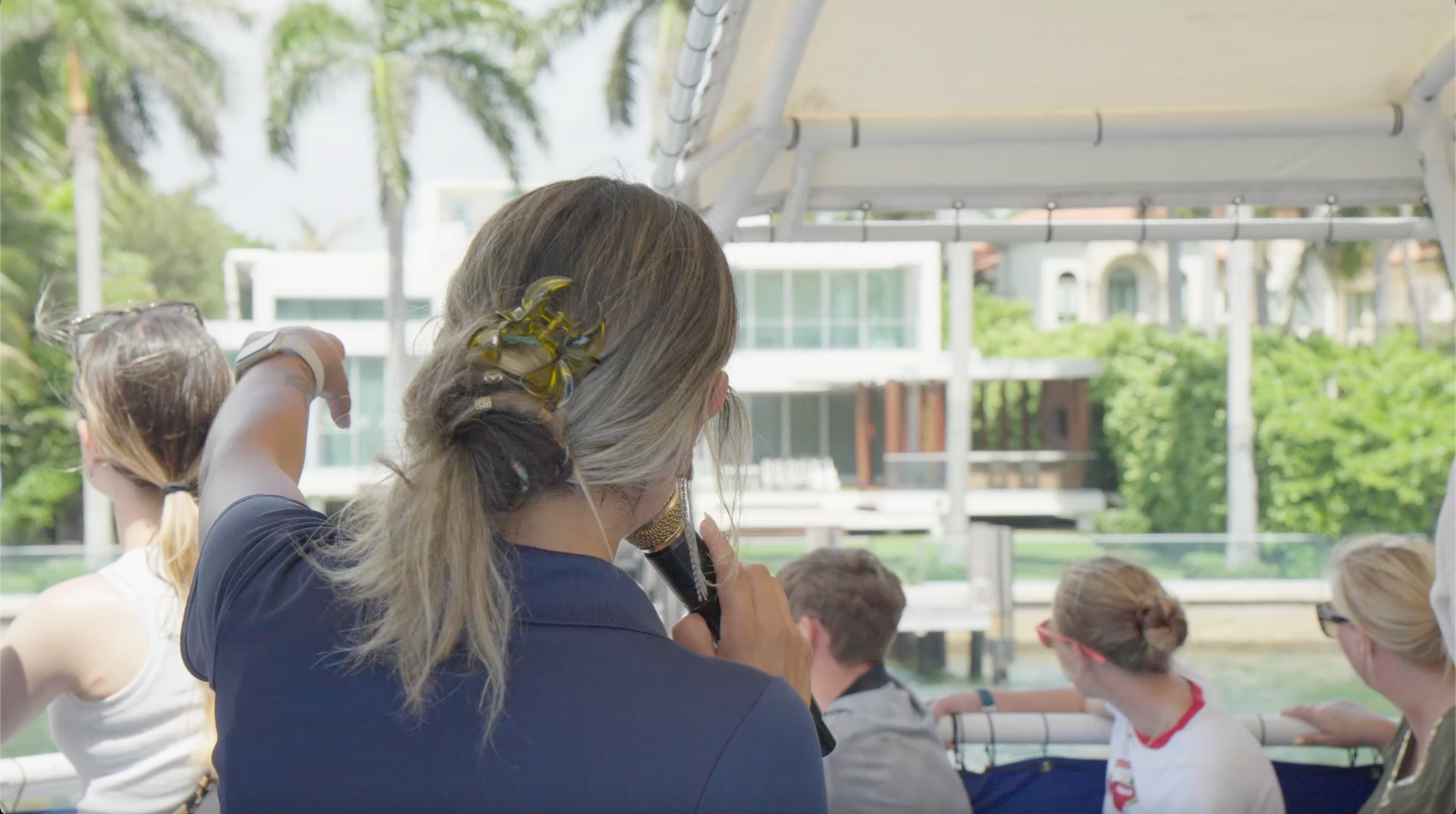 Miami Celebrity Boat Cruise Tour guide pointing pointing out mansions in Star Island Miami.